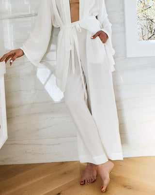 Woman in a white robe and towel in a bathroom with a window in the background