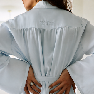 Light blue robe with 'Wifey' embroidery on the back, worn by a person.